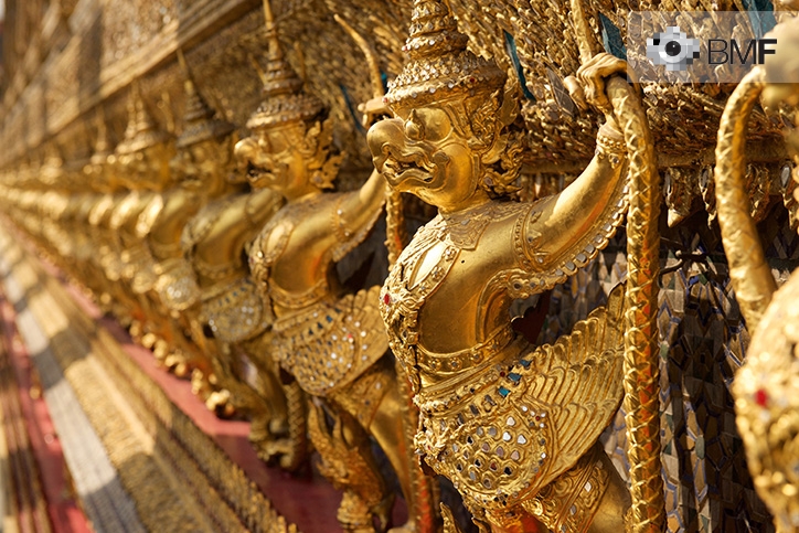 Una hilera de figuras doradas idénticas que parecen pájaros por su pico, con armadura y acompañados de un arma extravagante, adornan el Templo de Oro